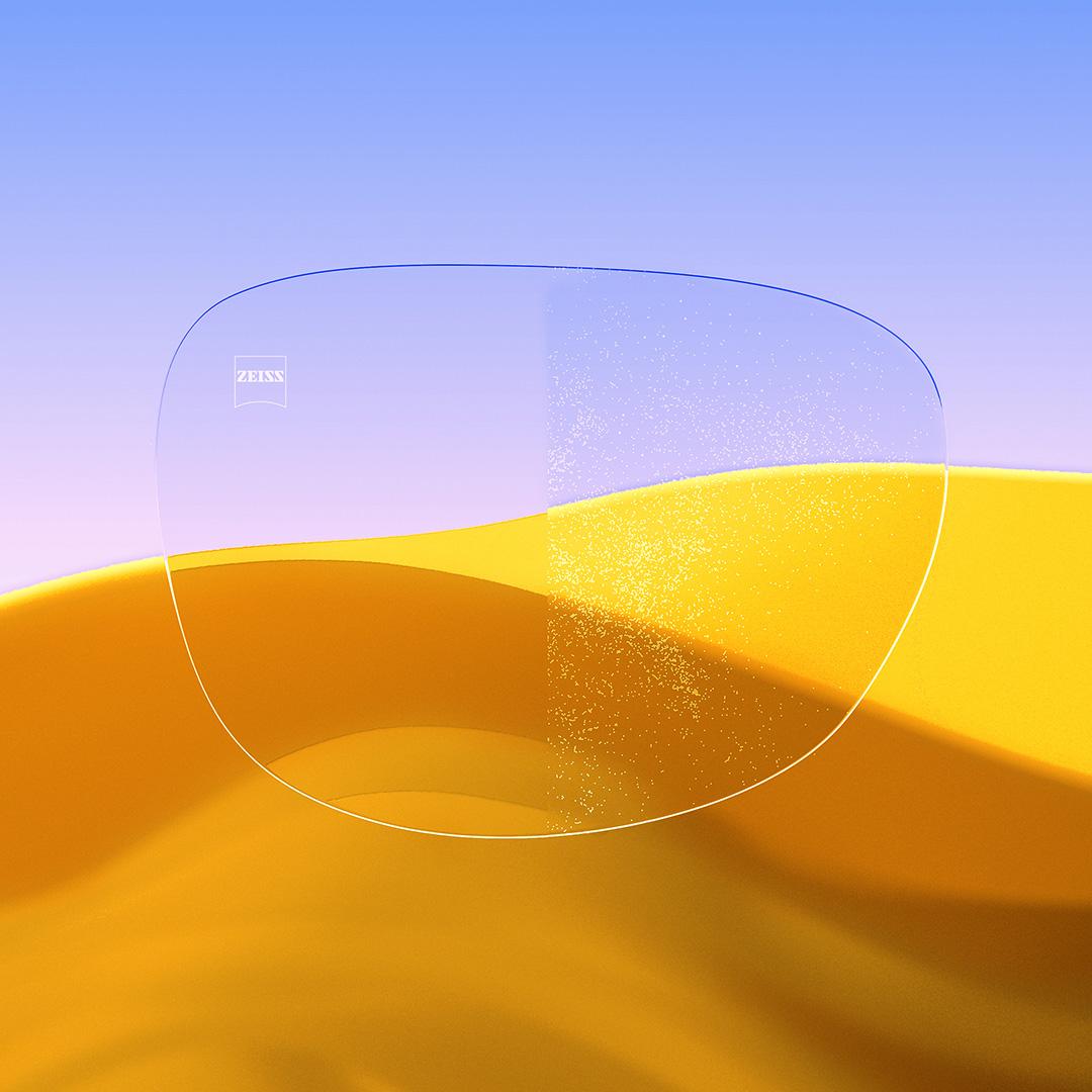 Uma lente de óculos dividida ao meio, com um lado nítido e limpo com ZEISS DuraVision Gold UV e um lado com poeira cobrindo a lente.