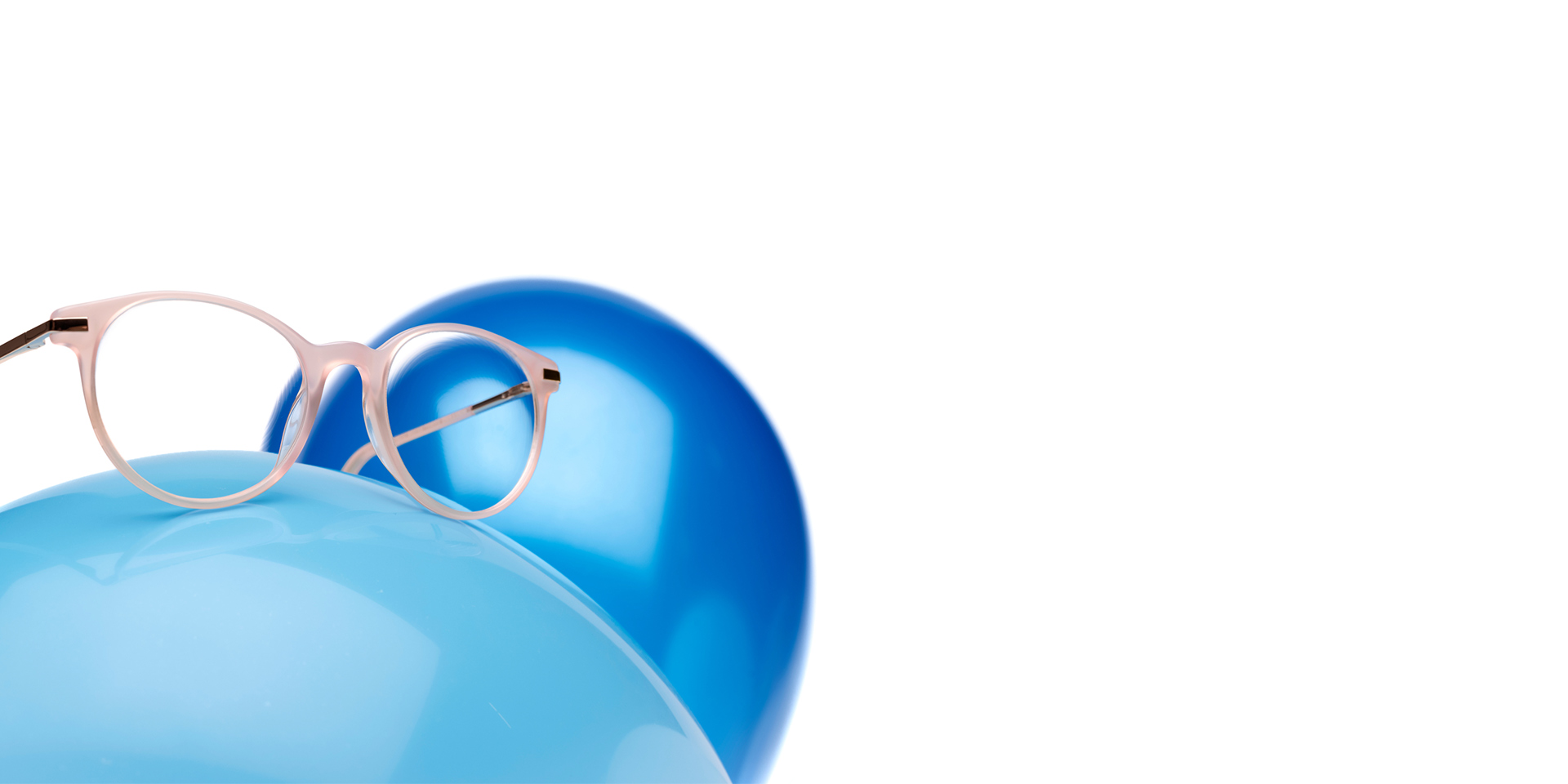 As lentes ZEISS MyoCare numa armação bege rosada são mostradas dentro de um balão azul claro Ao fundo, outro balão azul ligeiramente mais escuro.
