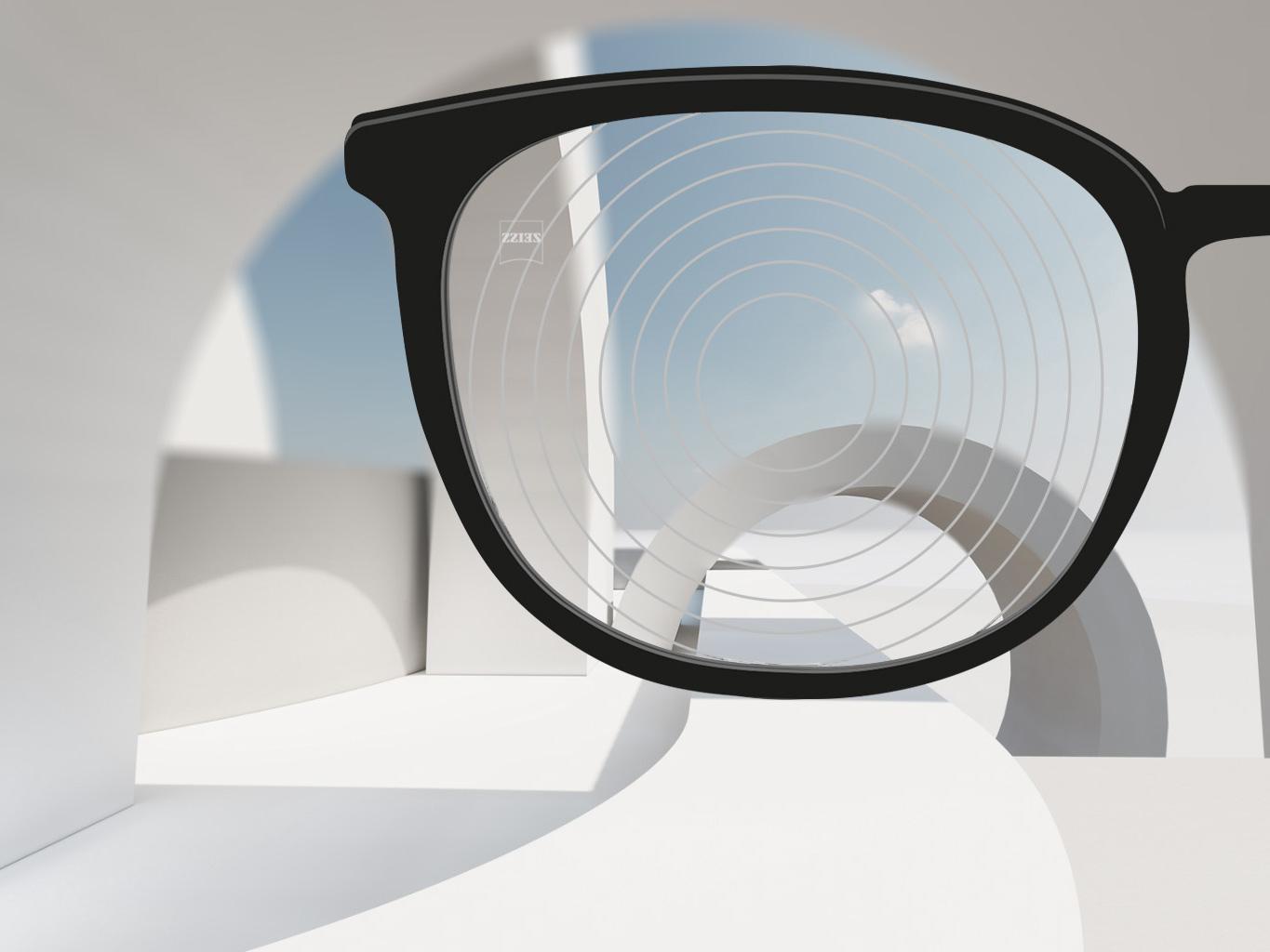 Imagem ampliada de uma armação preta e uma lente de gerenciamento de miopia ZEISS, com círculos concêntricos na sua superfície da lente. 