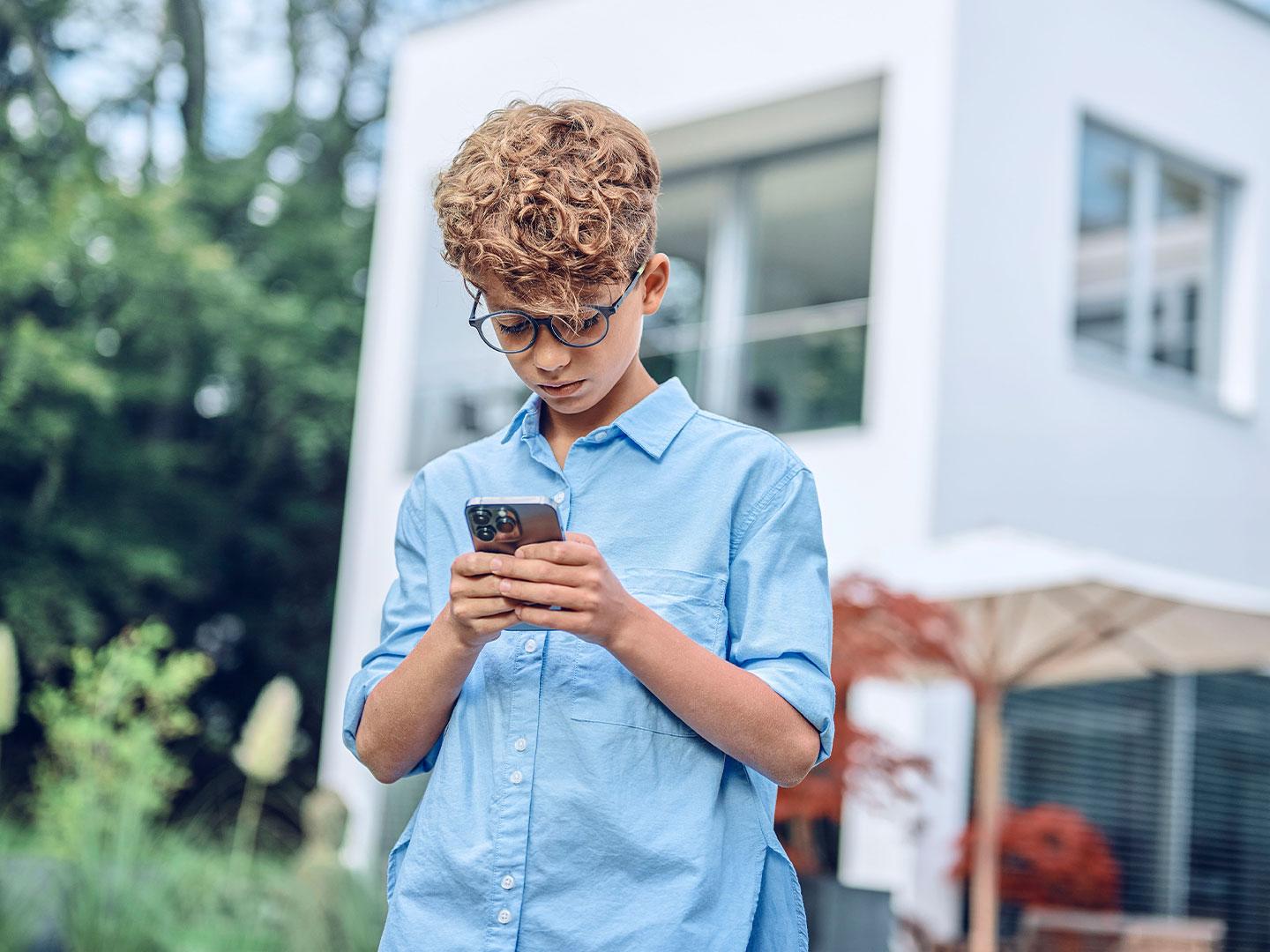 Jovem em ambiente externo olhando para o telefone