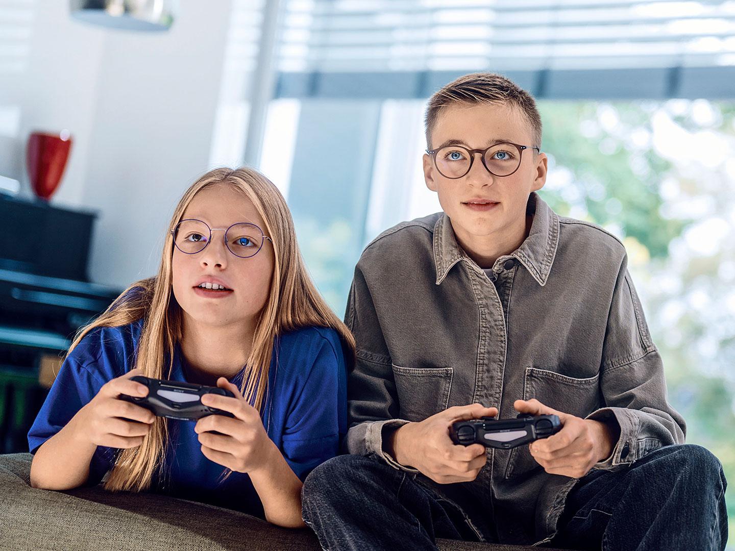 Um casal de adolescentes jogando videogames com consoles.