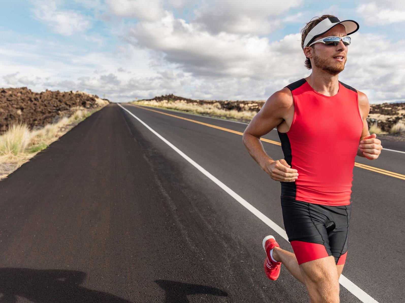 Imagem de um homem usando roupa e lentes esportivas enquanto corre em uma rua. 