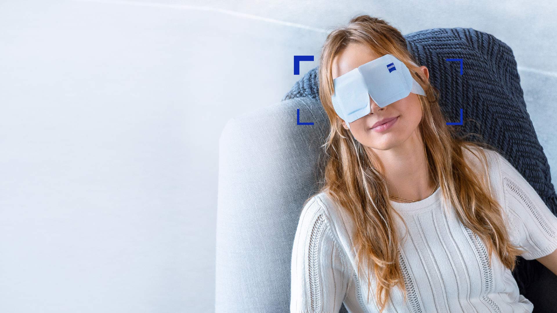 Mulher usando a ZEISS Warm Eye Mask enquanto relaxa em uma cadeira.
