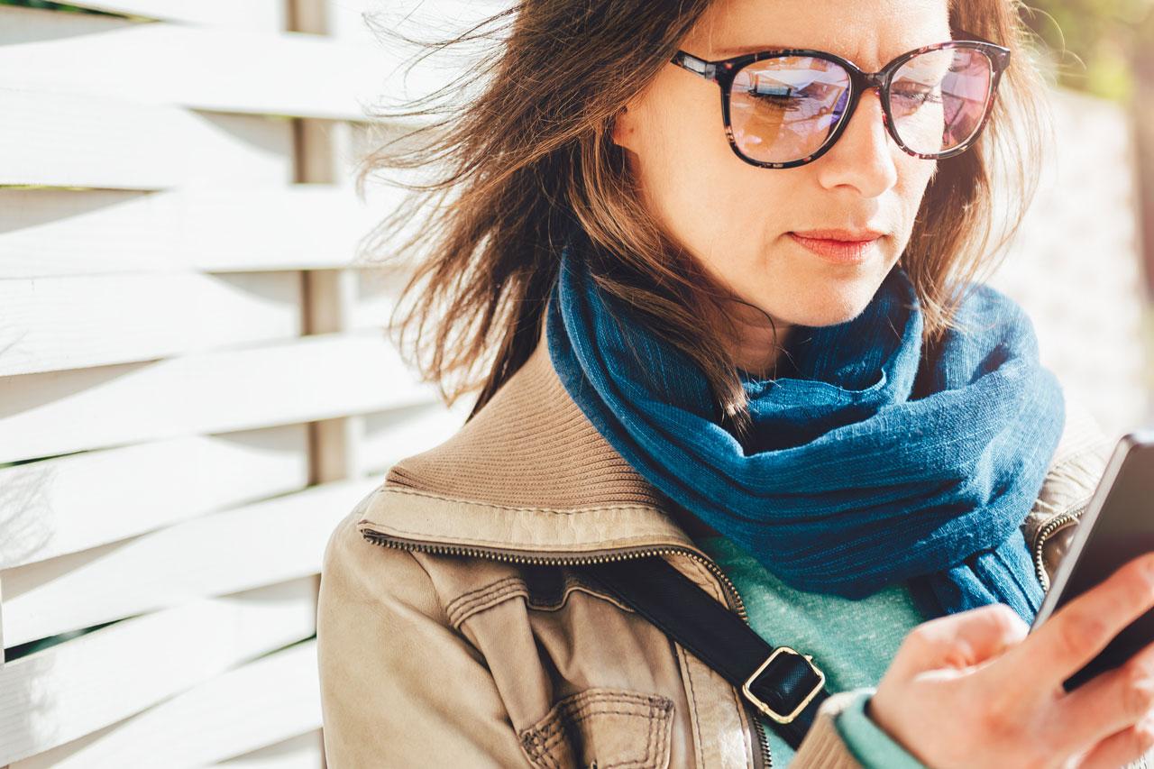 Mulher segurando uma xícara de café enquanto se movimenta e usa seu smartphone