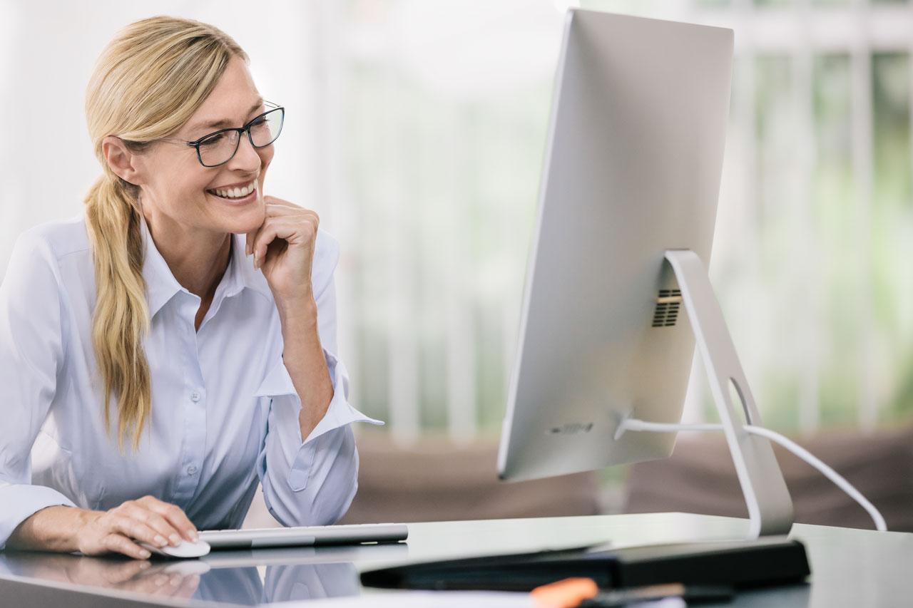 Mulher usando óculos e olhando uma tela de computador
