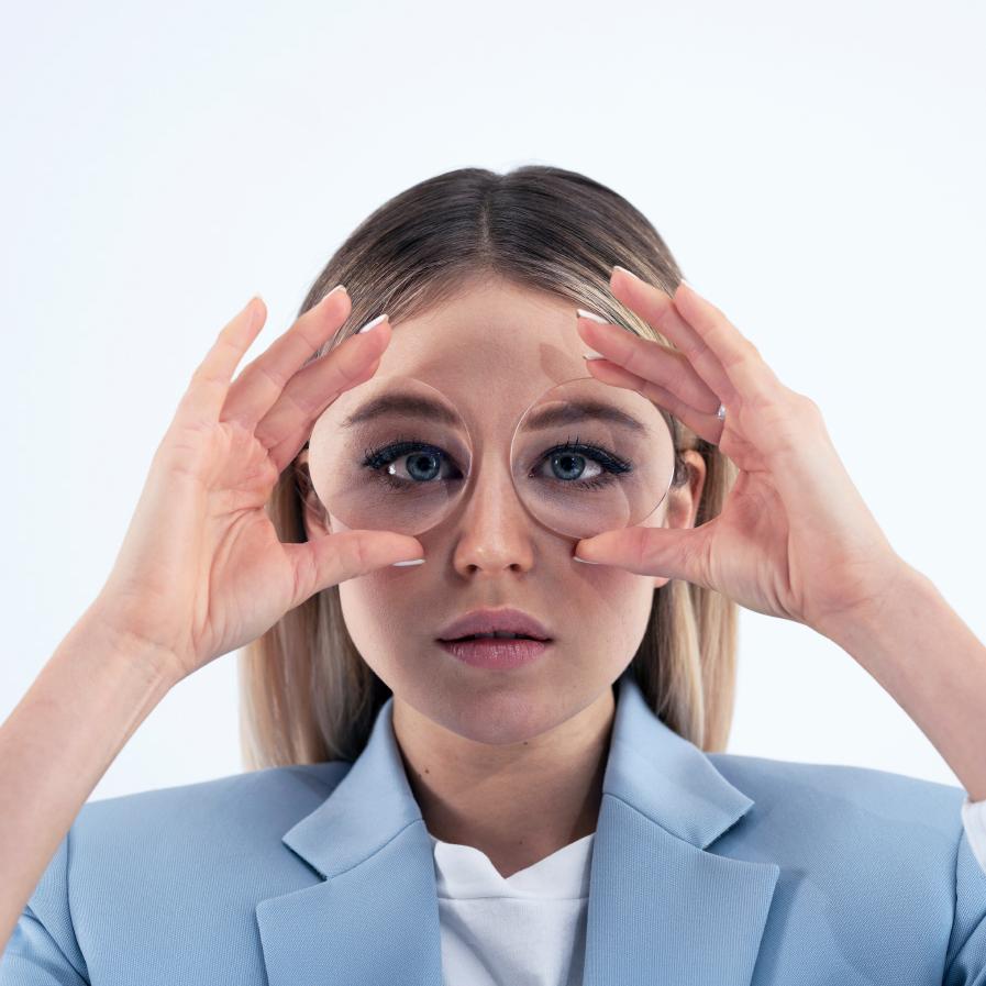 Mulher jovem segurando duas lentes grossas na frente dos olhos para mostrar o efeito de aquário.
