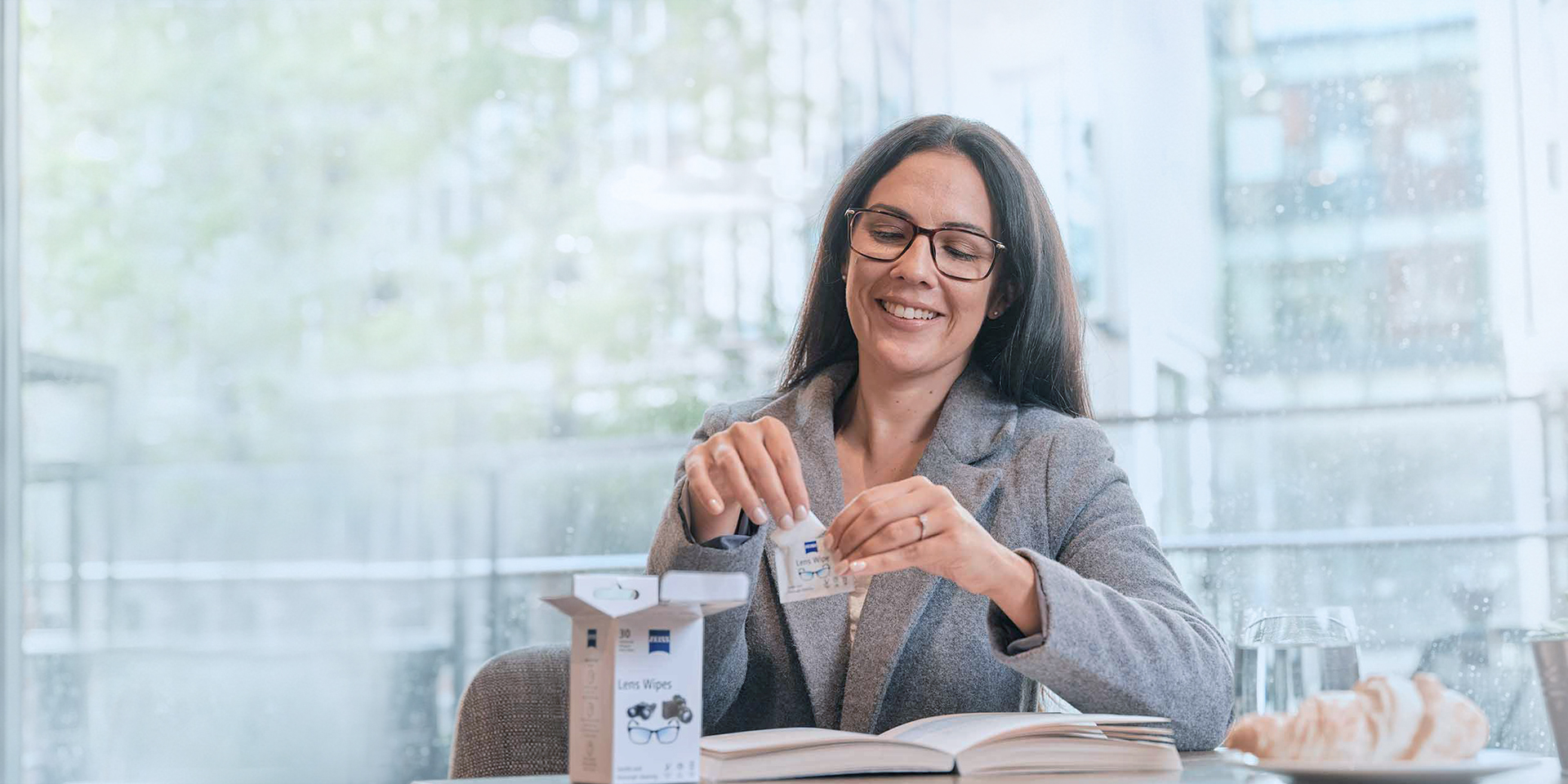 Mulher abrindo envelope de lenço para limpeza de lentes de óculos