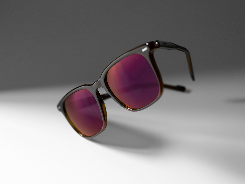 Imagem de uma lente de óculos de sol de grau da ZEISS com lentes na tonalidade Burgundy e tratamento ZEISS DuraVision Gold.