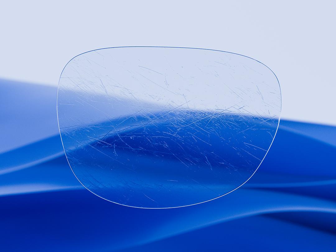 Imagem dividida exibindo uma lente ZEISS de um lado, caracterizada por sua nitidez e limpeza, e uma lente de óculos convencional arranhada do outro lado, destacando o contraste na durabilidade. 