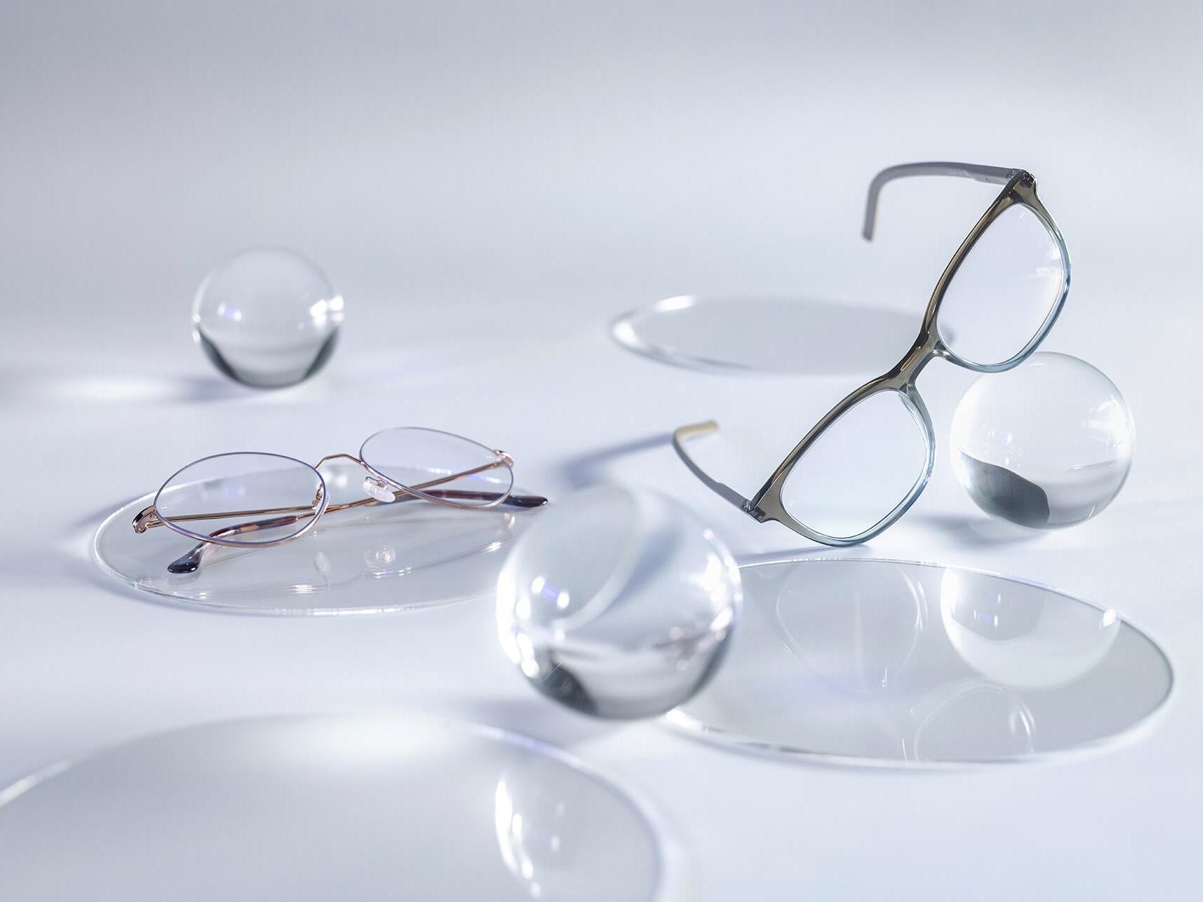 Óculos com lentes ZEISS e revestimento DuraVision® Silver sem nenhum reflexo em comparação com as esferas de vidro ao redor.