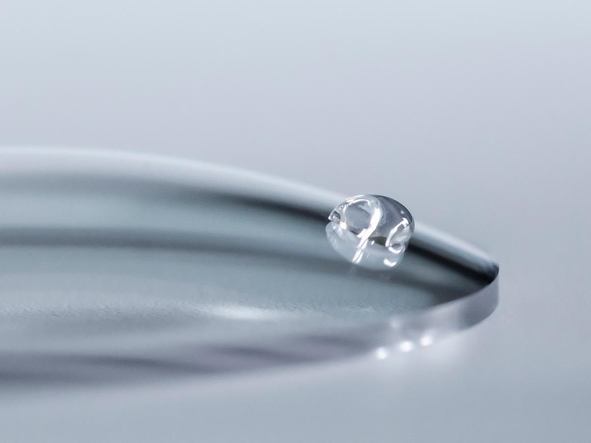 Uma gota de água desliza de uma lente ZEISS com revestimento limpo.