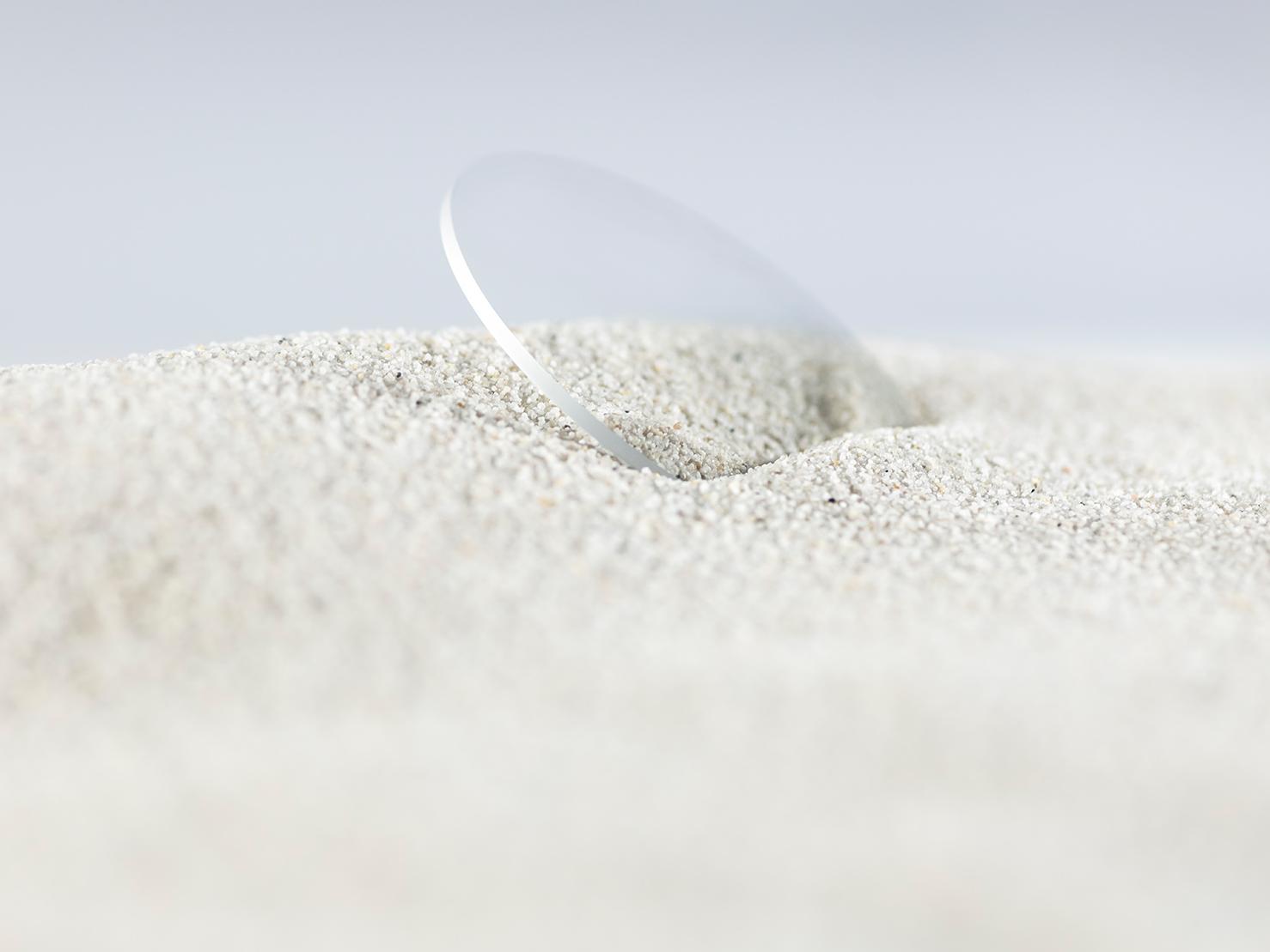 Lente ZEISS com revestimento durável coberta por areia grossa mas sem apresentar riscos.