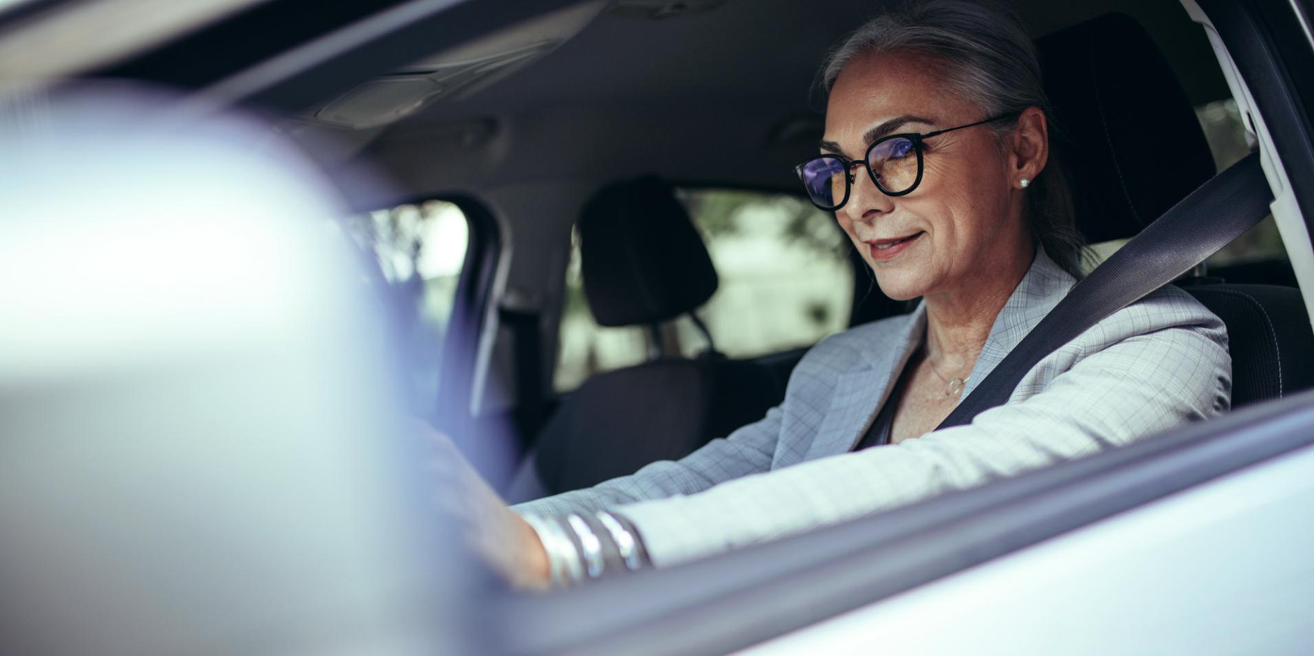 Mulher madura em um carro, usando óculos com lentes ZEISS DriveSafe.