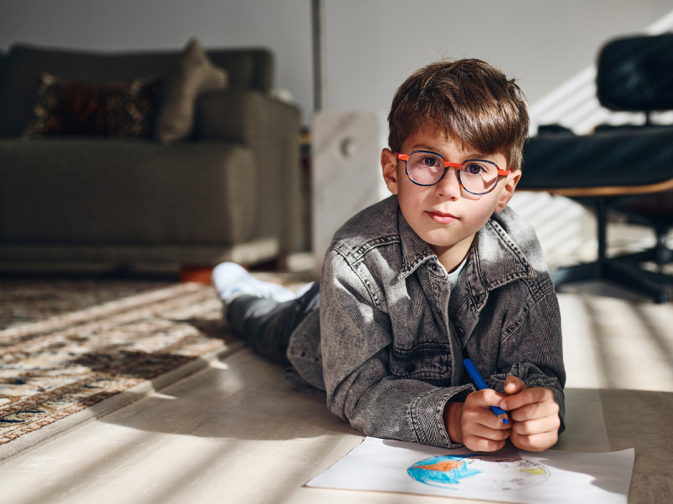 Menino pequeno usando as lentes ZEISS MyoCar e olhando diretamente para a câmera.