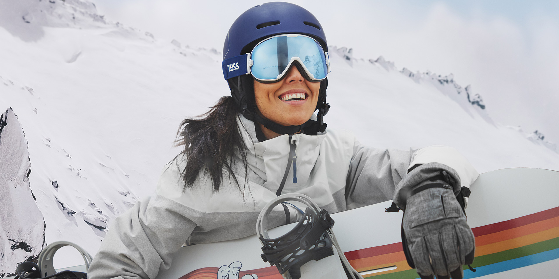 A young women wearing snow goggles with ZEISS Interchangeable technology and hold a snowboard.