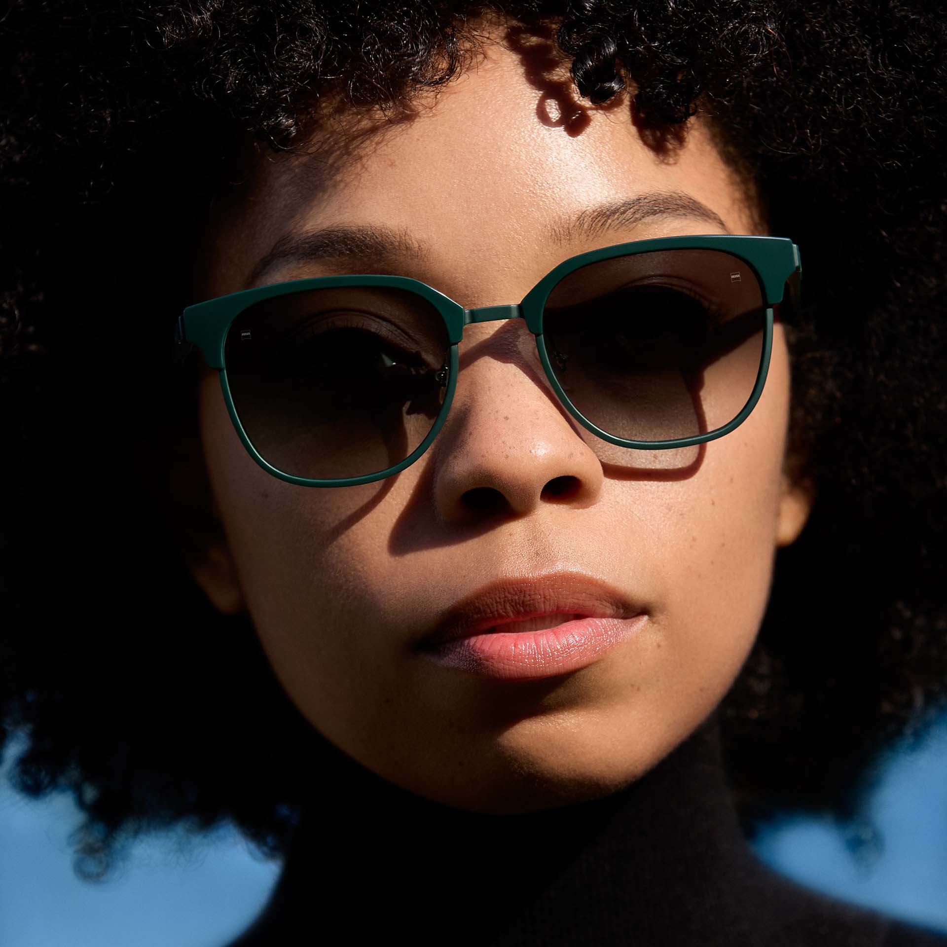 Mulher usando uma armação verde com lentes em tonalidade degradê. 